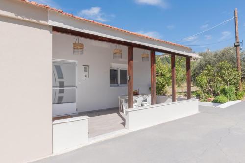 a white house with a large open porch at Pastida Olive Home in Pastida