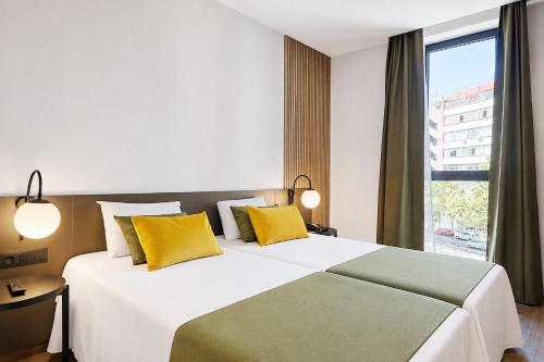 a bedroom with a large white bed with yellow pillows at DWO Colours Alcalá in Madrid
