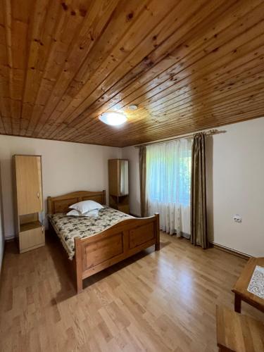 a bedroom with a bed and a wooden ceiling at Poteca Ursului in Arefu