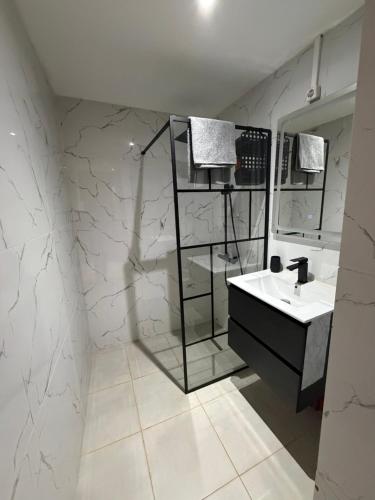 a white bathroom with a sink and a mirror at Résidence les maquis in Koungou