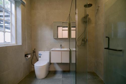 a bathroom with a toilet and a glass shower at Rasah Golfers Cottage in Tanah Rata