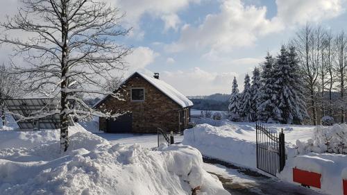a house covered in snow next to a fence at Sixine House in Ovifat