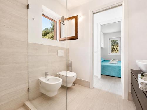 a bathroom with a toilet and a glass shower at Renew Terrace F with Swimming Pool 70m from the Beach in Baja Sardinia