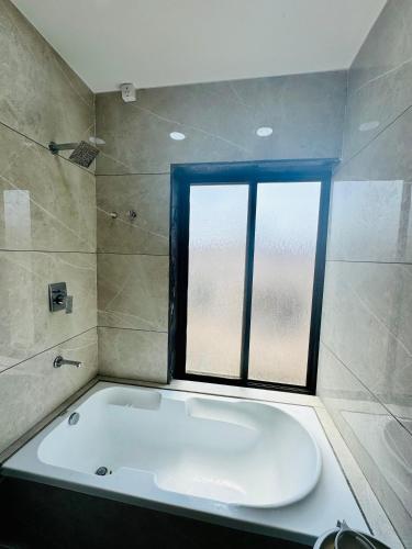a bathroom with a bath tub and a window at Hotel JD Fortune in Anand