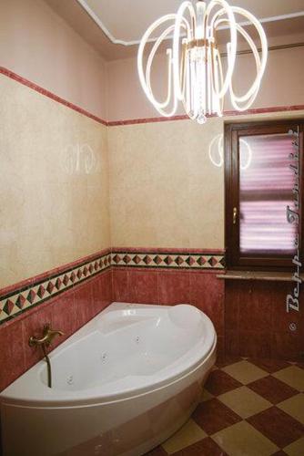 a bathroom with a white tub and a chandelier at B&B Montisclari in Monchiero