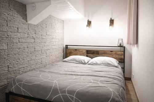 a bed in a room with a brick wall at Chez Louis - Central Triplex in Rethel