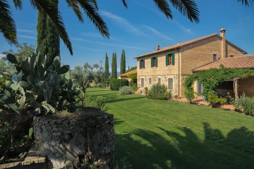 a garden with a house and a palm tree at Agriturismo Bandinelli in Castiglione della Pescaia