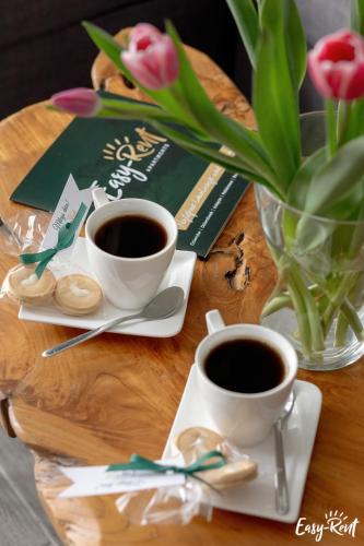 two cups of coffee on a wooden table with flowers at Piastowska in Pobierowo