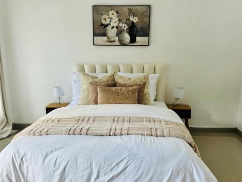 a bedroom with a white bed with two night stands at Revo Apartments in Lusaka