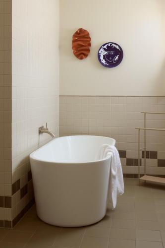 a white tub in a bathroom with a plate on the wall at Owston Hotel in Fremantle