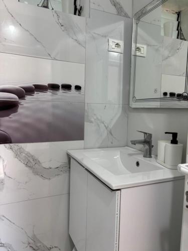 a white bathroom with a sink and a mirror at Kambi rooms in Himare