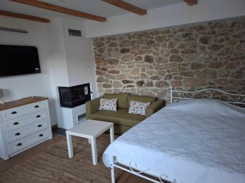 a bedroom with a stone wall with a bed and a couch at Nevoliani stone house in Florina
