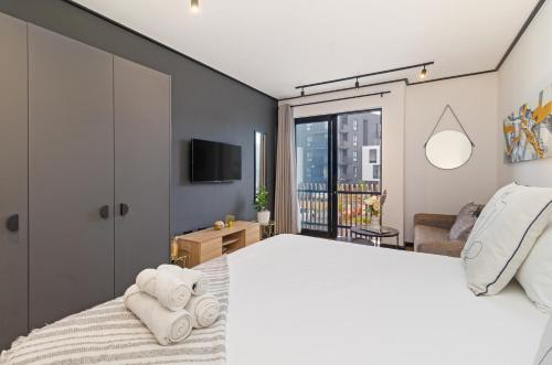a bedroom with a large white bed and a tv at Nine Palms Studio Retreat Century City in Cape Town