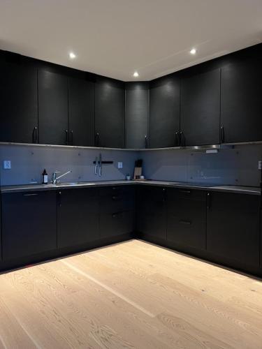 a kitchen with black cabinets and a wooden floor at Oppheimhamna 10c in Bø