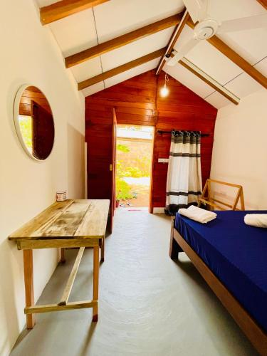 a bedroom with a bed and a wooden table at Mermaid Hostel in Trincomalee