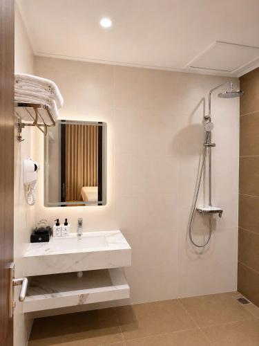 a white bathroom with a sink and a shower at Adora Hotel Khe Sanh in Khe Sanh