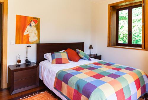a bedroom with a colorful bed and a window at Holly Country House in Paredes de Coura