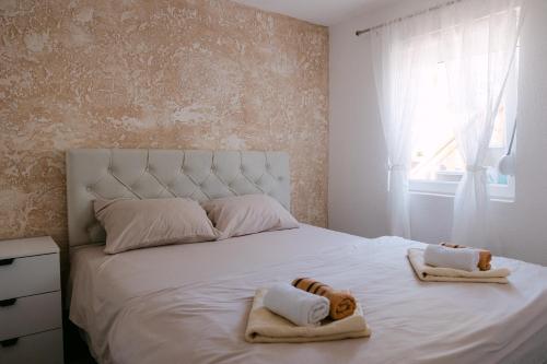 a bedroom with a white bed with towels on it at Apartmani Dejavu na Drini in Ljubovija