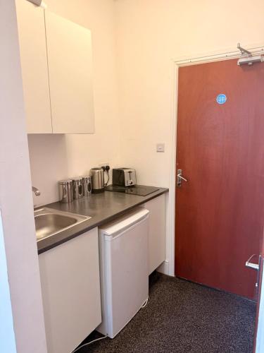 a small kitchen with a sink and a red door at Colne Hideaway in Colne