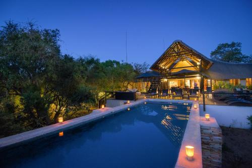 a swimming pool in front of a house at night at Vuyani Safari Lodge in Hoedspruit