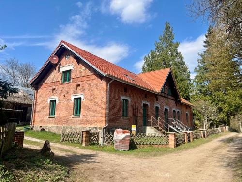 an old brick building with a red roof at Försterei Kalkhorst Ferienhaus am Naturschutzgebiet mit großem Garten in Neustrelitz