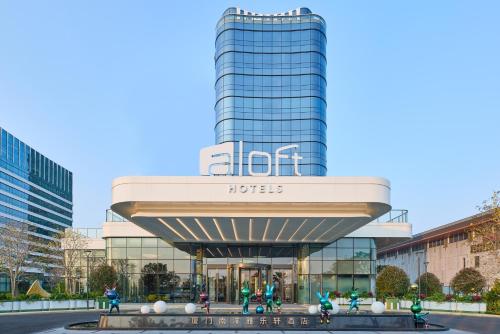 a tall building with people in front of it at Aloft by Marriott Xiamen Xiangan in Xiamen