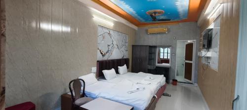 a bedroom with a white bed and a tv at HOTEL BUDDHA in Kushinagar
