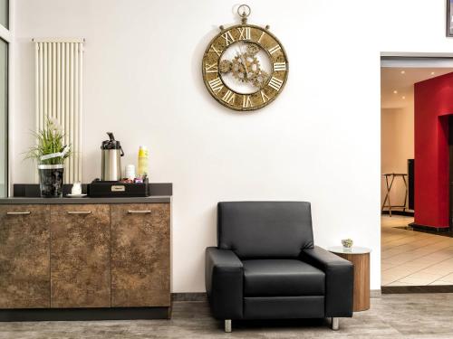 a chair in a room with a clock on the wall at ibis Styles Hotel Gelsenkirchen in Gelsenkirchen
