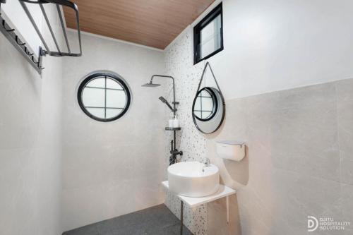 a white bathroom with a sink and two windows at Diamond Cabin 3 in Diyeng