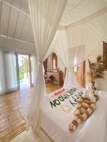 a bedroom with a white bed with a sign on it at Romantic private villas Buvillas nusa penida in Nusa Penida
