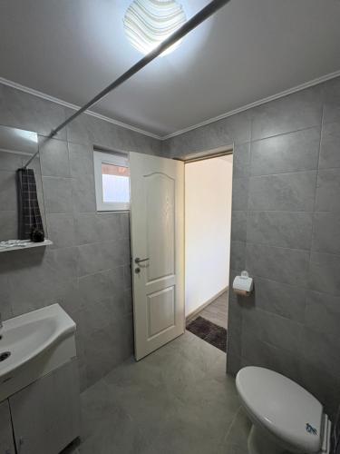 ein Badezimmer mit Toilette und weißer Tür in der Unterkunft Vila Aron in Tuzla