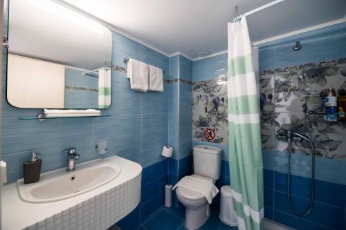 a blue bathroom with a sink and a toilet at Antonis Studio in Archangelos