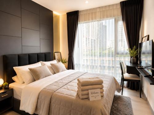 a bedroom with a large bed with a desk and a window at Ultra luxury Condo in Bangkok