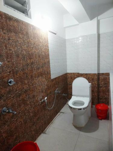 a bathroom with a toilet and a red trash can at grace homestay in Darjeeling