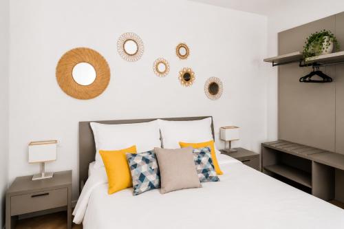 a bedroom with a white bed with pillows and mirrors at Yellow Apartment in Bari