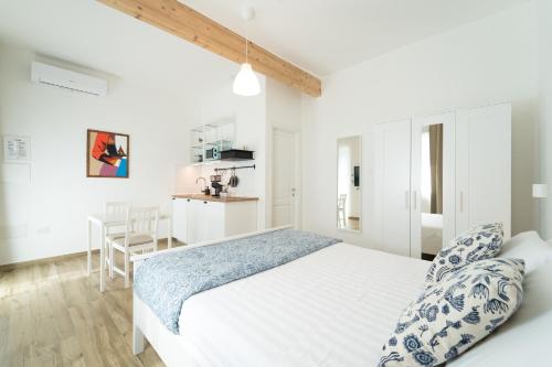 a white bedroom with a bed and a kitchen at Velis - art & hospitality in Posada