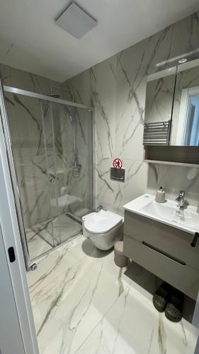 a bathroom with a shower and a toilet and a sink at EVA Premium Luxury Apartments - Limak Diamond Residence in Skopje