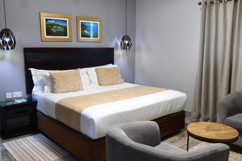a bedroom with a large bed and two chairs at Villa de Chazha Guesthouse in Francistown