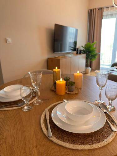 a wooden table with plates and glasses and candles on it at EVA Premium Luxury Apartments - Limak Diamond Residence in Skopje