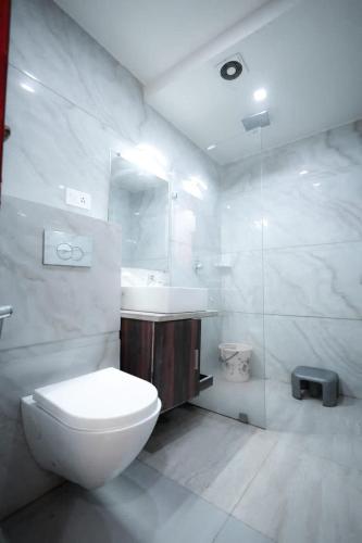 a white bathroom with a toilet and a sink at The Crown Hotel Agra near Taj Mahal in Agra