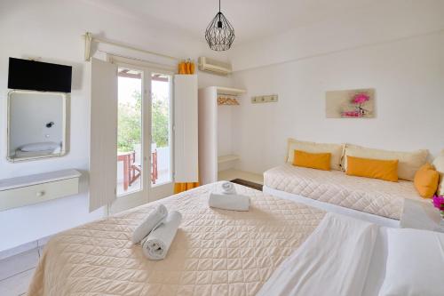a white bedroom with two beds and a tv at Marili Apartments Studios in Parasporos