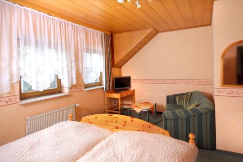 Schlafzimmer mit einem Bett, einem TV und einem Stuhl in der Unterkunft Gästehaus Stolzenberg in Hallenberg