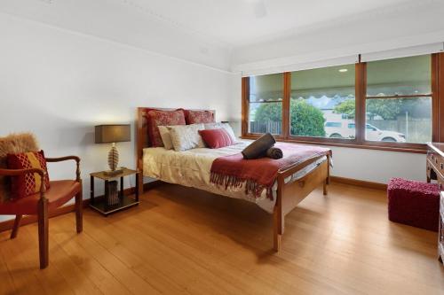 a bedroom with a bed and a chair and a window at Retro Retreat in Highton