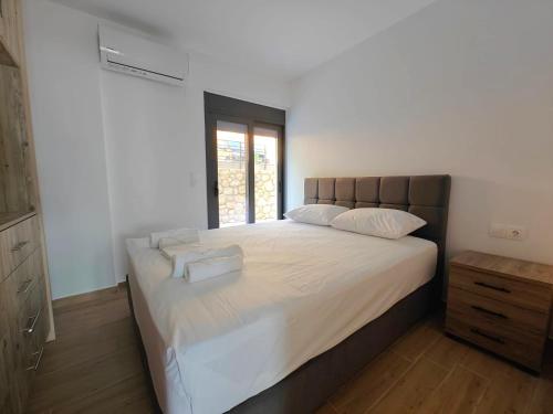 a bedroom with a large bed with white sheets and a window at Episkopos Escape in Nikiana