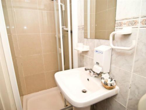 a small bathroom with a sink and a shower at Skylark Guest House in Hounslow