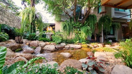 a garden with a pond in front of a house at SHAN Villas Sukhumvit ฌานวิลล่า สุขุมวิท in Bangkok