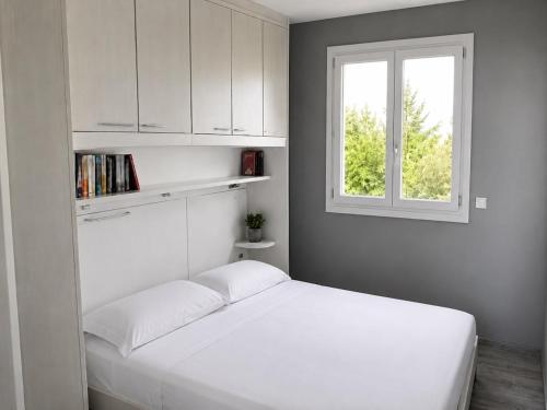 a white bedroom with a bed and a window at BellaVista - Vallecrosia in Vallecrosia