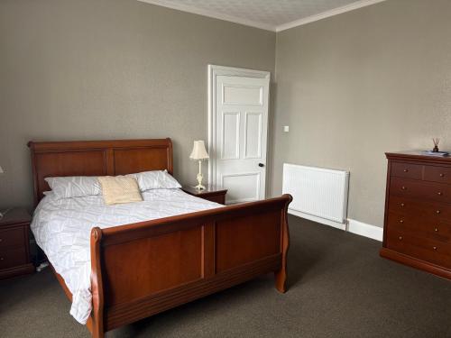 a bedroom with a bed and a dresser and a door at Preston Villa, spacious ground floor apartment in Buckie