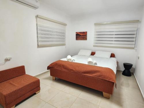 a bedroom with a bed and a couch and a window at וילה נחל טביה in Arad