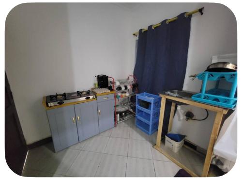 a small kitchen with blue cabinets and a table at Iringa Hillside backpackers in Iringa